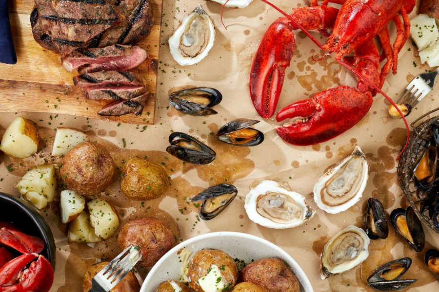 Aerial view of PEI potatoes, lobster, mussels. oysters and beef served on brown butcher paper