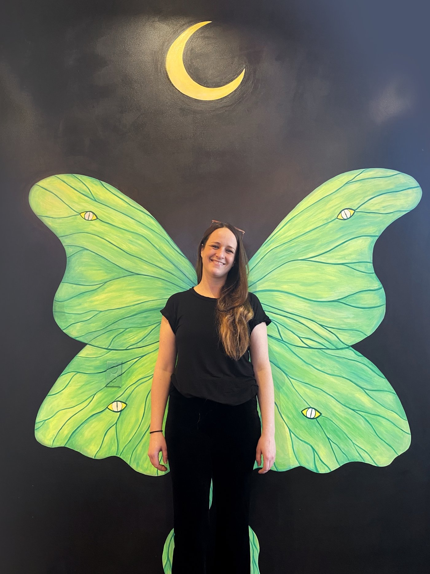 Artist Ashley Anne Clark stands in front of her mural at Founders Food Hall in Charlottetown