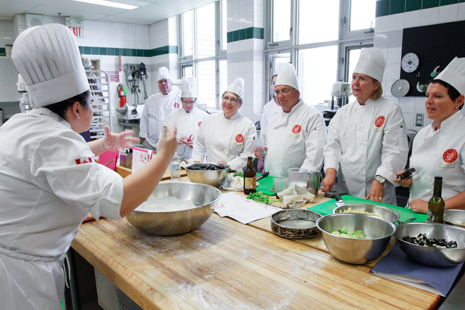 Adults watch Chef instructor at Culinary Bootcamp in kitchen, PEI