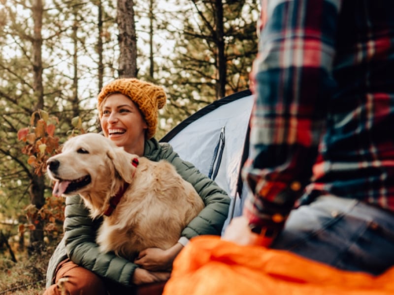 A woman holding her dog and sitting next to a man in the outdoors