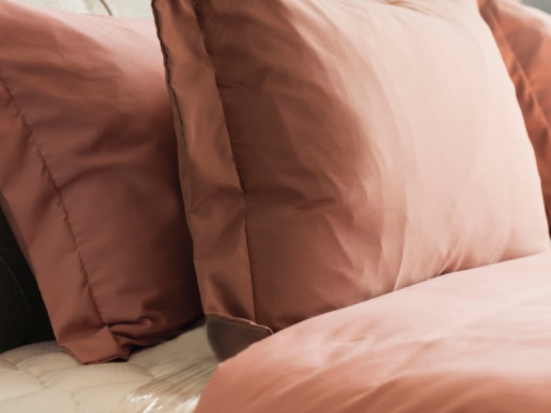 Close up of tufted headboard, pillows and blanket on bed