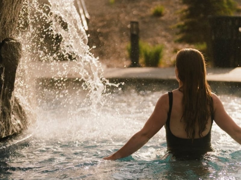 Woman enjoying cold plunge with waterfall at Mysa Spa