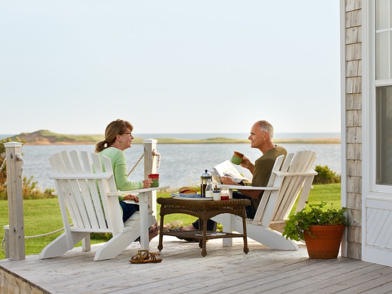 Couple sits on patio enjoying morning coffee with waterview in background