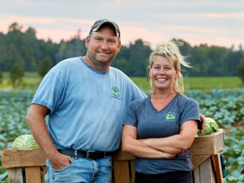 Greg & Tania MacKenzie stand in a field of cabbage on their farm