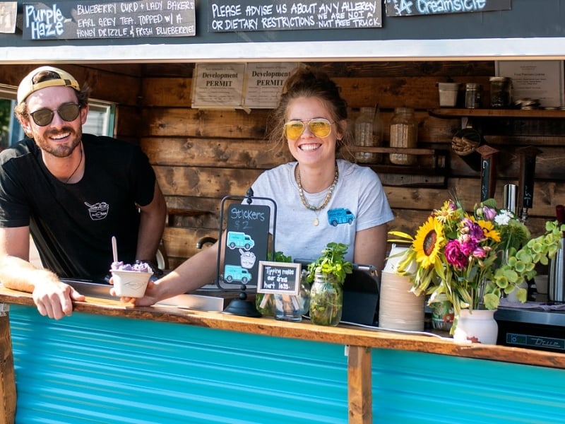 Two people serve rolled ice cream from Food Truck