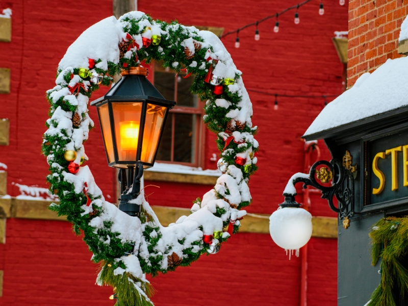 Snowy winter wreath on top of lamp post in downtown Charlottetown with red building in background