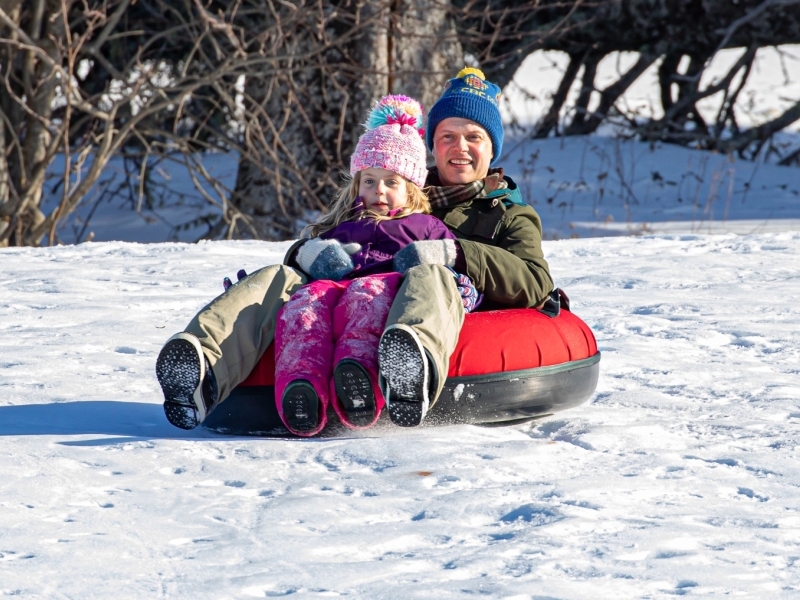 Adult male and child on tube on sledding hill, PEI
