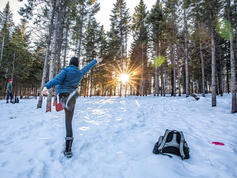 person throws disc on winter disc golf fairway