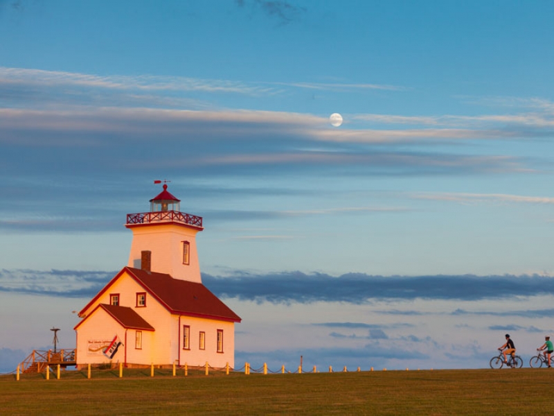 2 people biking next to lighthouse