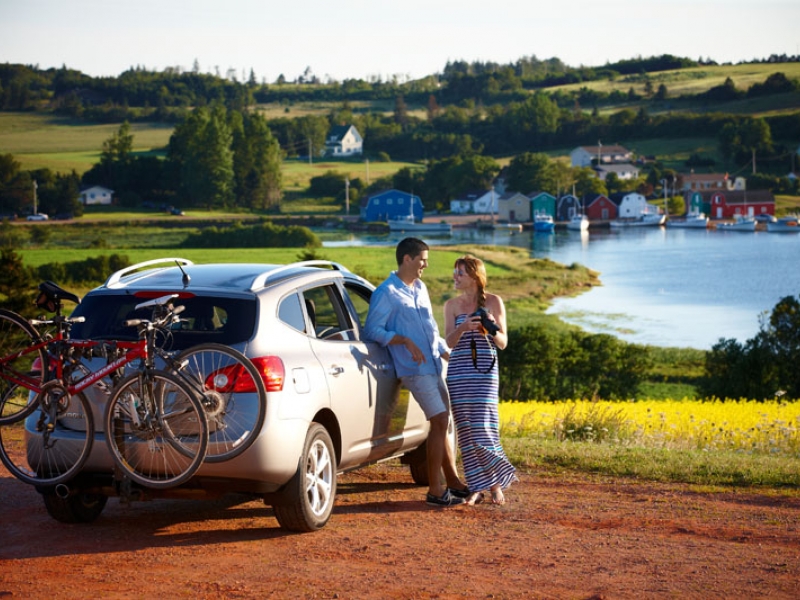 Couple leaning on car by water