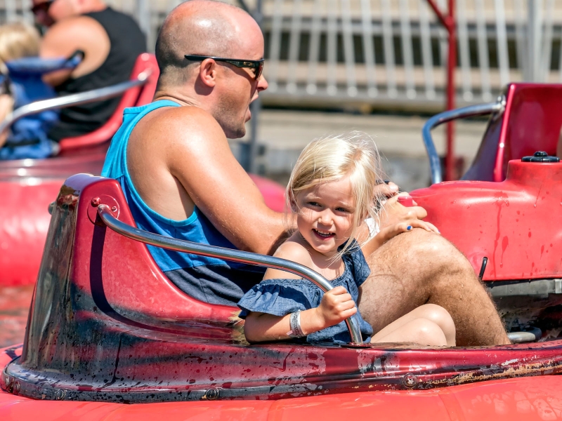 Adult male and young girl enjoy bumper boats at Sandspit Amusement Park
