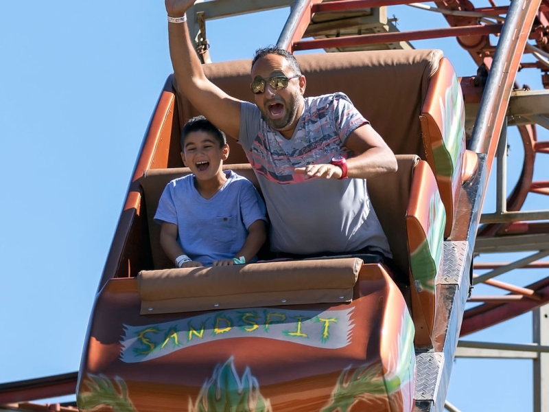 Adult male and child enjoy roller coaster at Sandspit Amusement Park