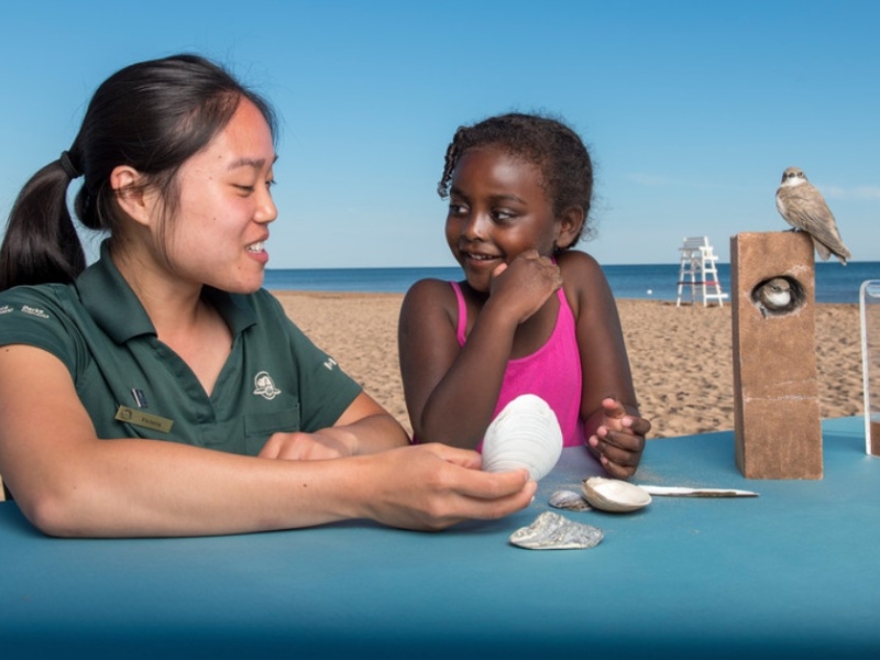 Parks Canada staff person interacts with young girl at the beach about beach ecology