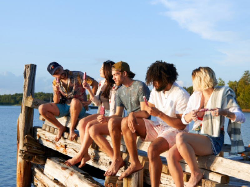 A group of friends sitting on a wooden dock by the water