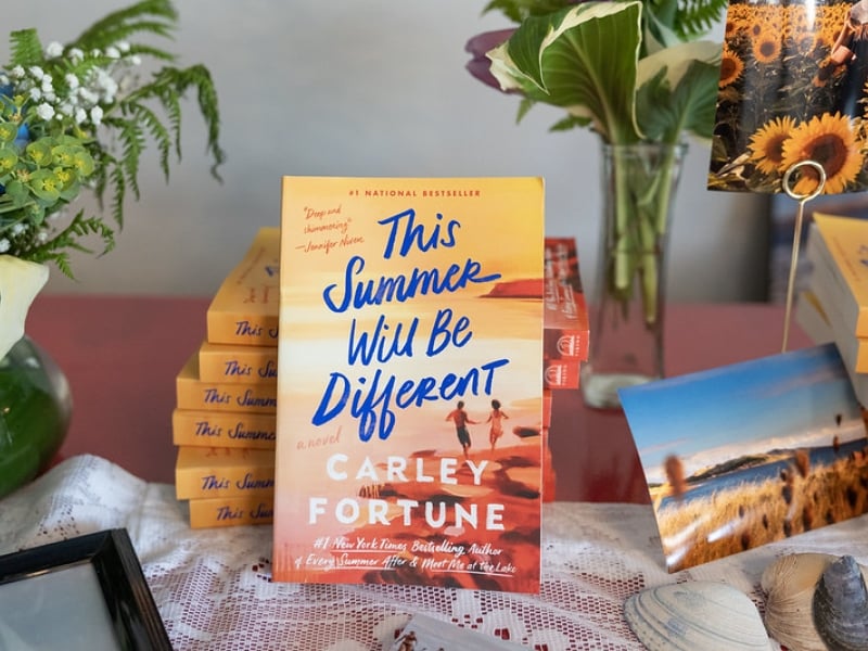 Stack of This Summer Will Be Different books on display with PEI postcards