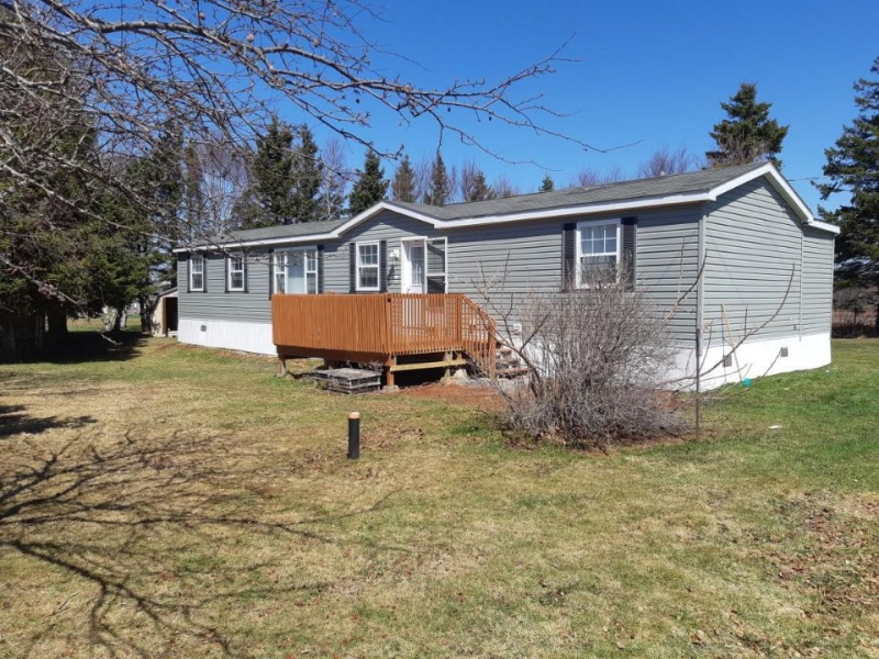 outside photo looking at a grey mini home with small deck on front