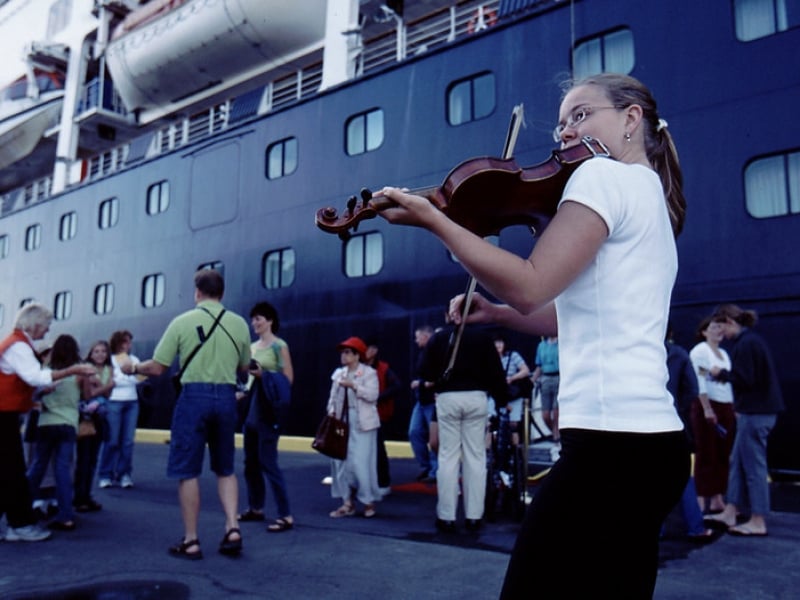 Young fiddler plays for cruise passengers dockside