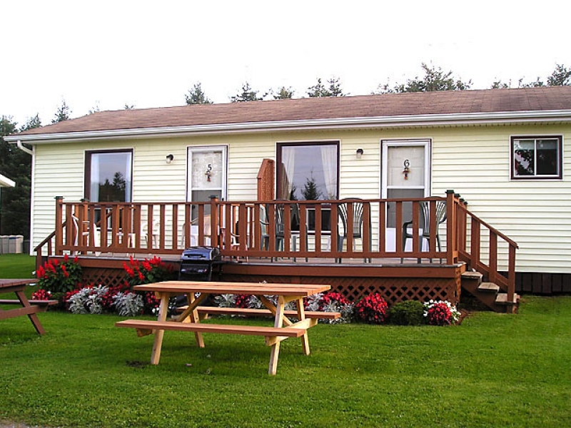 Cottage with yellow siding, front deck and outdoor picnic table 