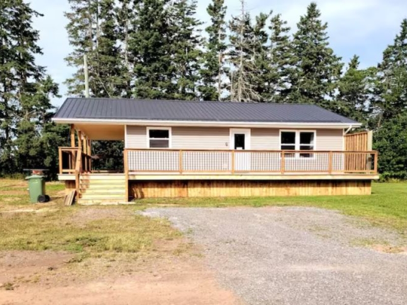 outside front view of beige cottage and trees behind it