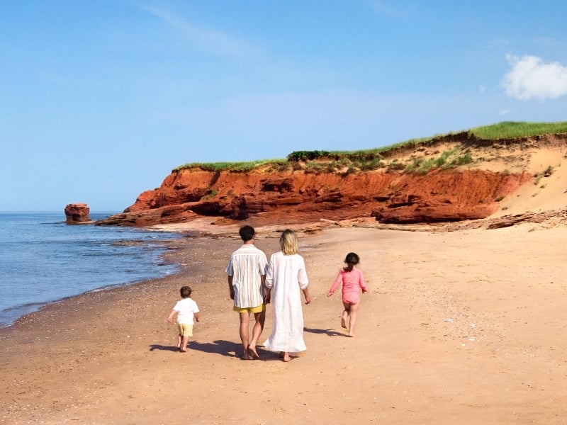 Family of four walk the beach at Thunder Cove under clear blue summer sky