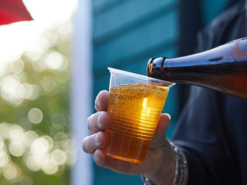 Person pours a glass of beer in outdoor setting