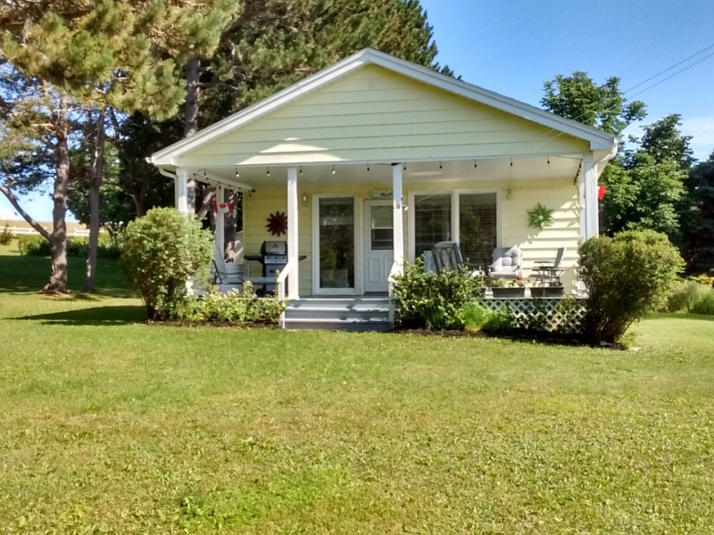 outside view of a yellow cottage with nice front porch