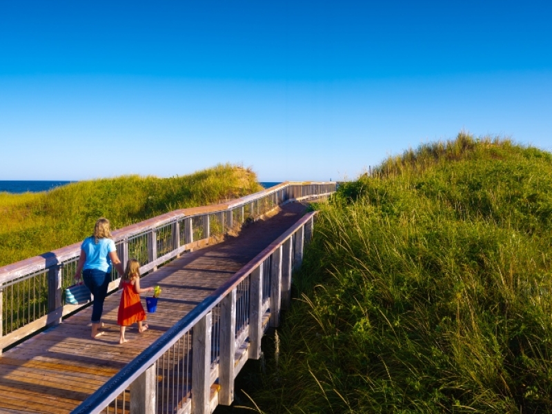 Mother and child walk on boardwalk to Brackley Beach