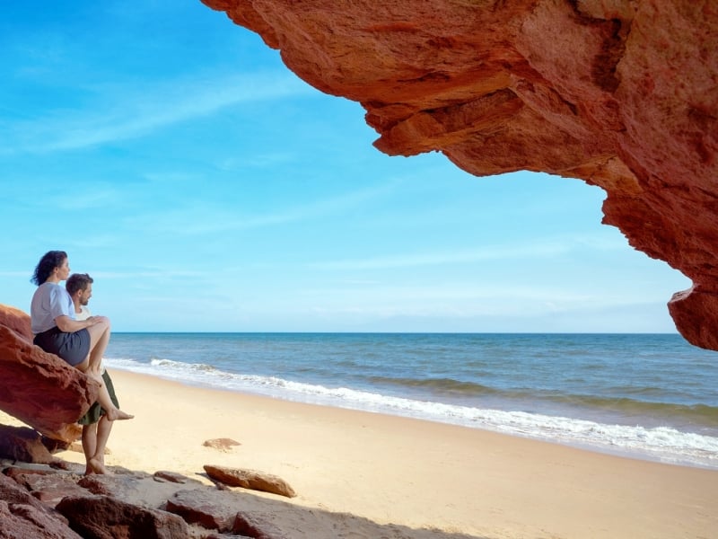 Couple sit on rock watching the waves at Red Point Provincial Park