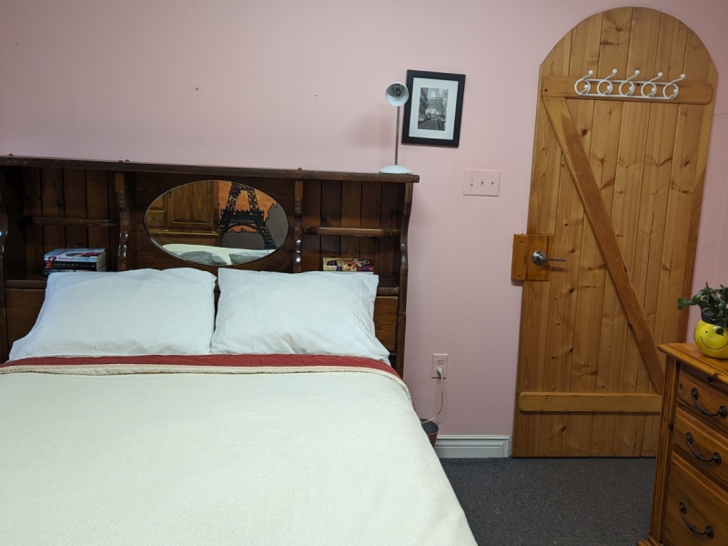Double bed with cream bedspread and blush rose walls with pine door