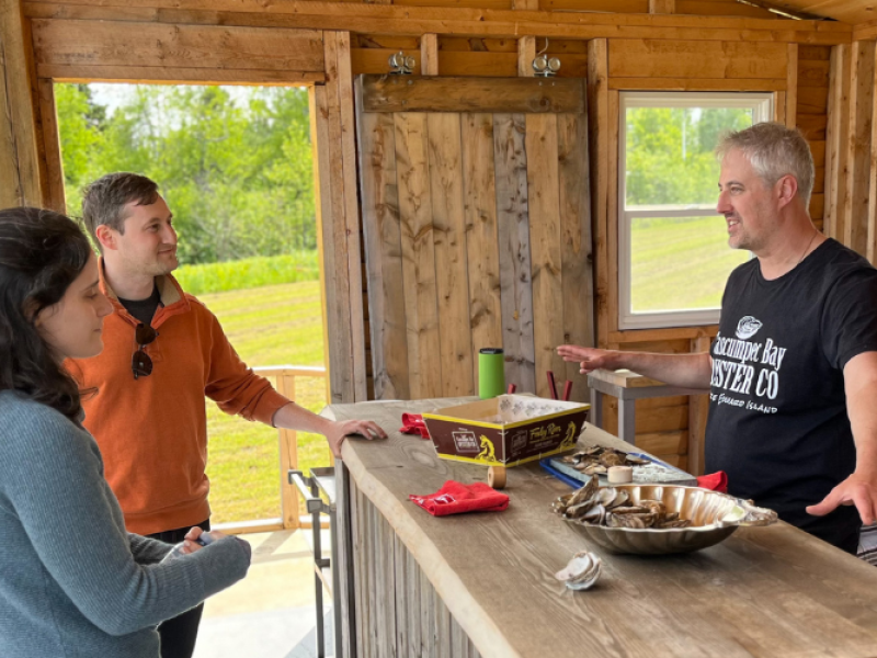 Oyster shucker talks with guests at Cascumpec Bay Oyster Co.