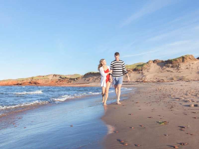 Male and female couple walking along Cavendish Beach