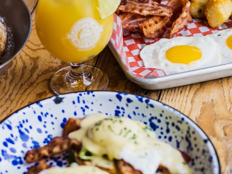 Plated eggs benedict, mimosa and eggs sunnyside up at Copper Bottom Brewing
