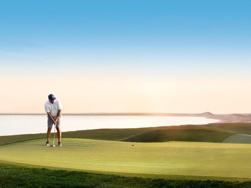 Golf on putting green with ocean view in background