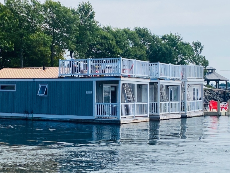 Three grey floating cottages on the water at Peake's Quay with rooftop decks