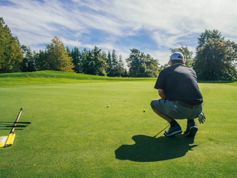 Male golfer squatted down eyeing the ball on the course