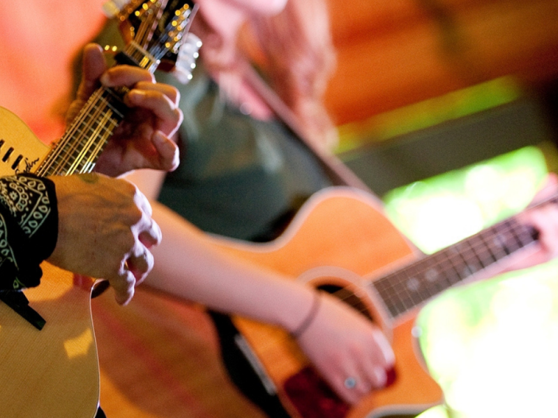 CLose-up of two people holding guitars and performing on stage 