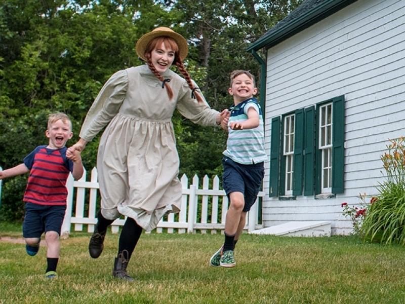 Anne of Green Gables performer plays with children on lawn of Green Gables Heritage Place