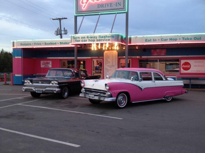 Exterior view of Gillis' Drive In with two classic cars sitting out front