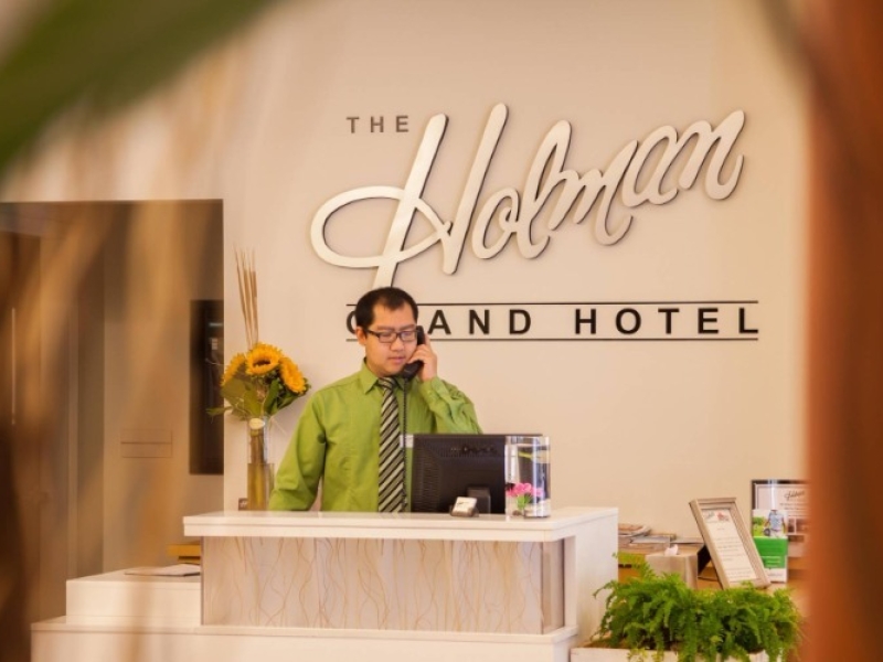 Staff member on phone at front desk of the Holman Grand Hotel