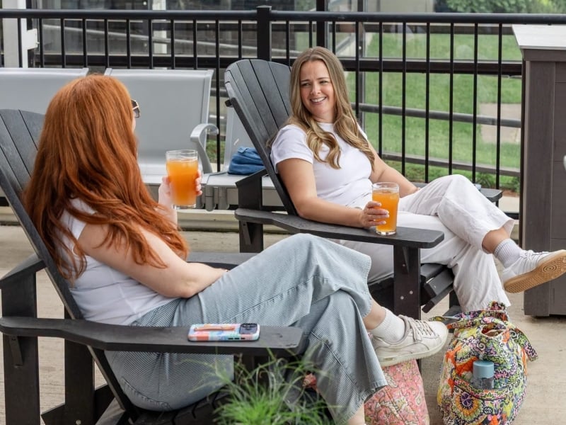 Two people relaxing in the Dock, outdoor boarding lounge at YYG
