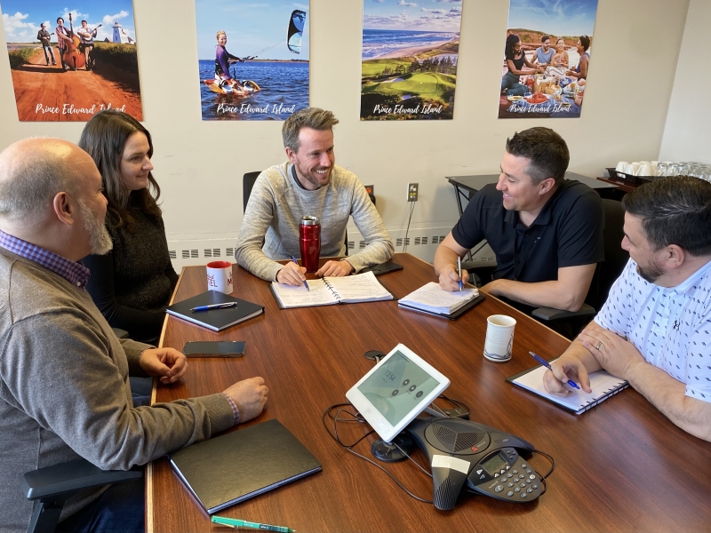 Group of five staff people meet at a boardroom table