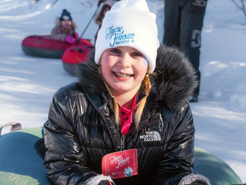 Young girl on sledding tube at Jack Frost Festival in winter