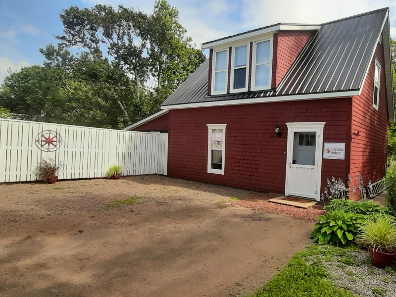 The front of the Little Red Bard surrounded by trees and a white fence
