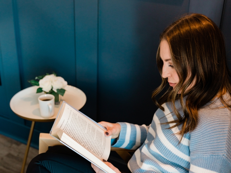 Woman sitting with a cup of tea and reading a book