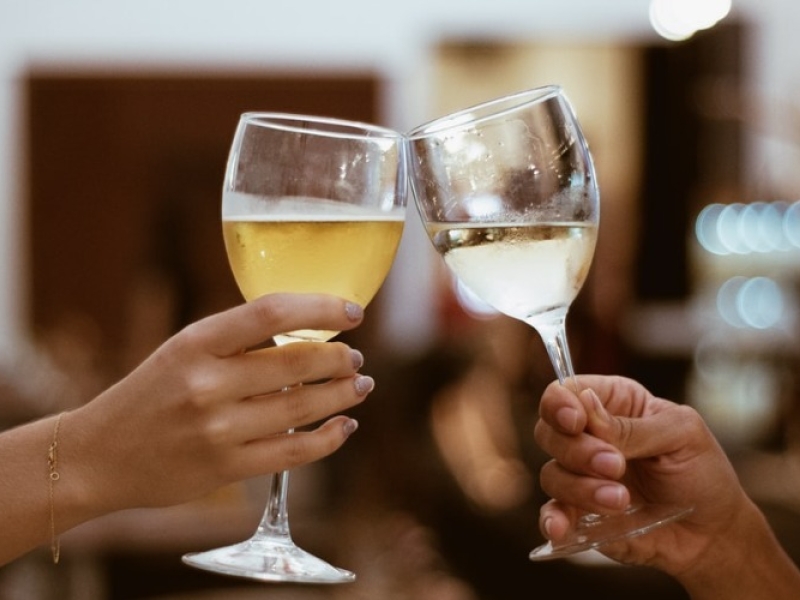 Stock image of two persons tapping glasses of wine