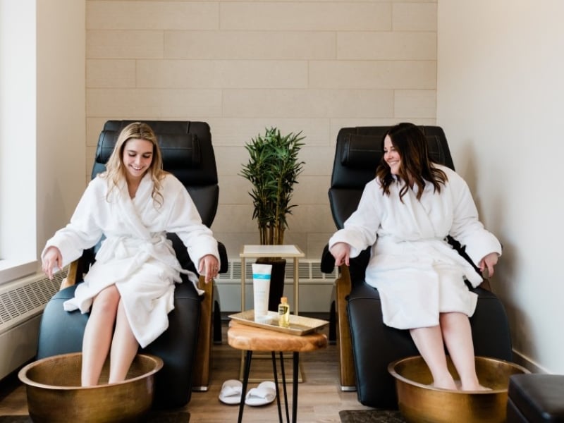 A couple of women enjoying a pedicure, dressed in white robes