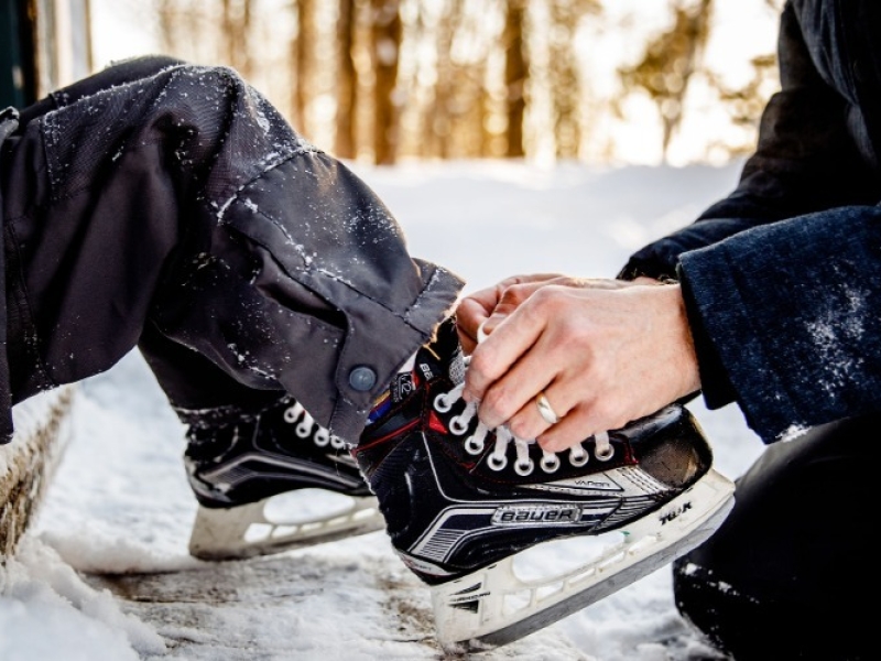 Adult tying a child's skates outdoors