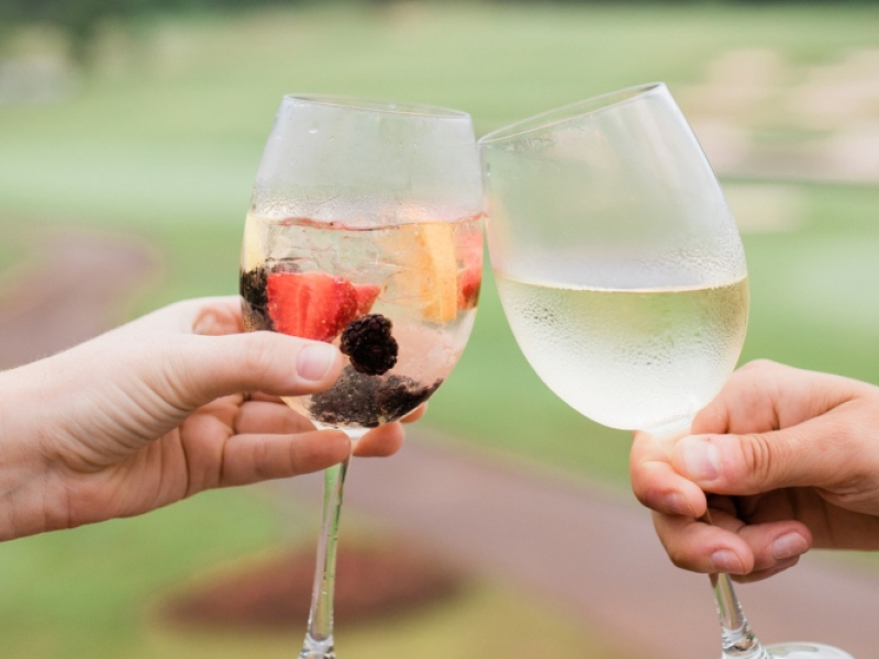 Duo toast with wine glasses with golf course in background