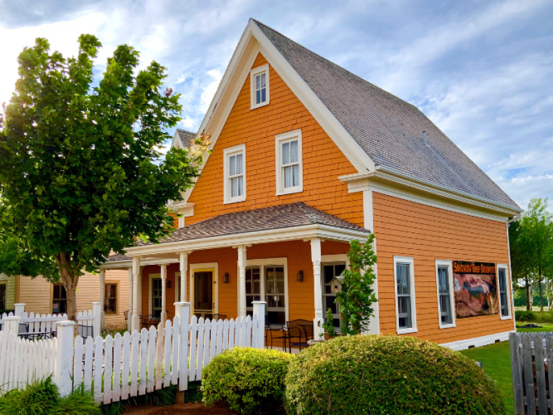 Orange historic house with verandah and white picket fence in the front yard