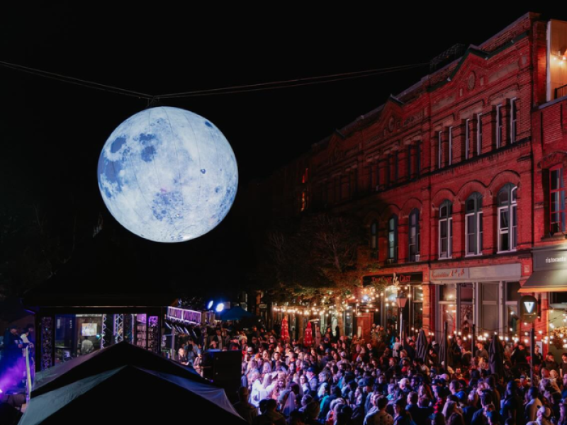 People attending festival on Victoria Row after dark with giant inflatable moon overhead